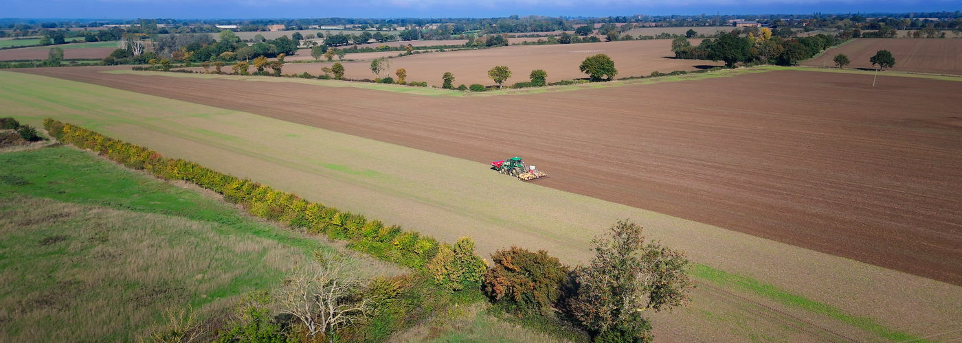 Tine Drill Toolbar working across a large field at sunset